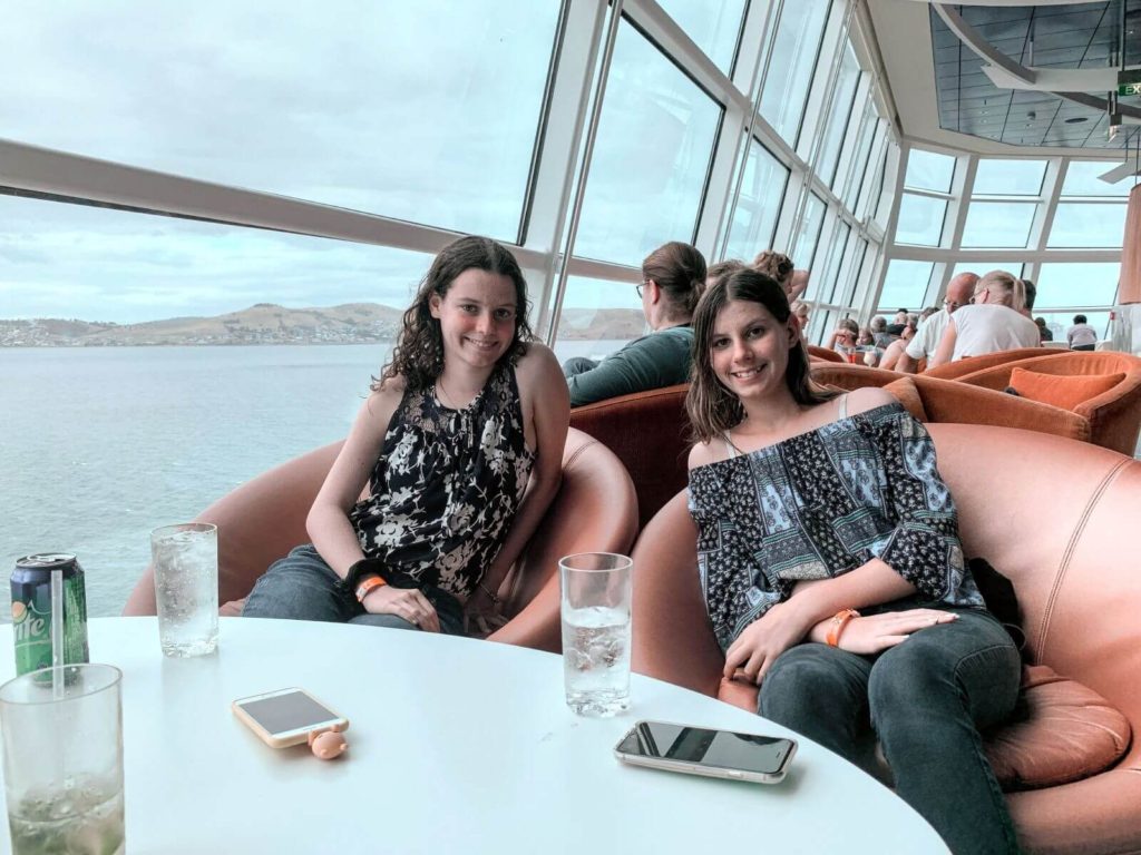 two people sitting at a table in an observation lounge on a cruyise ship