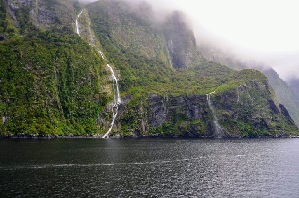 a waterfall cascading down a forest clad mountain cliff