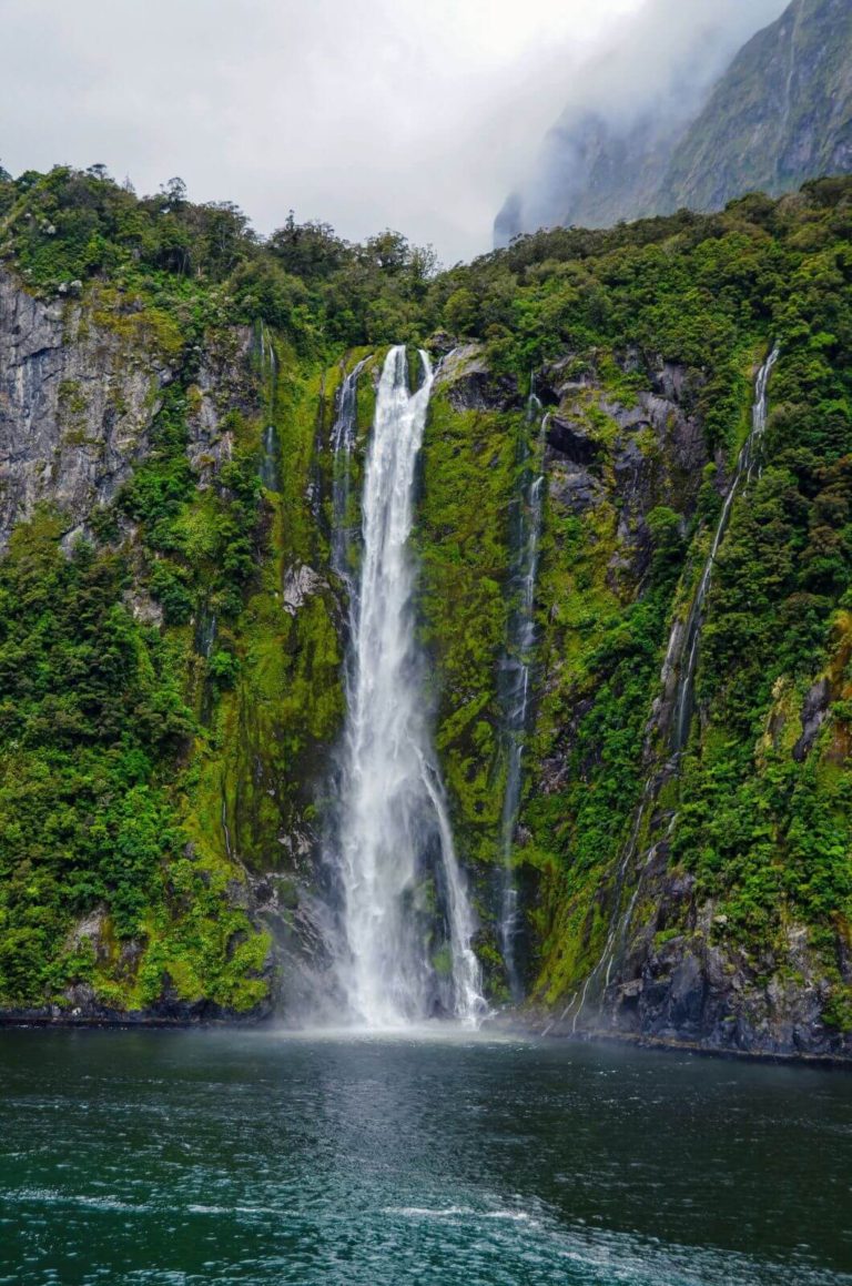 a tall waterfall gushing into the fiord from the cliff top