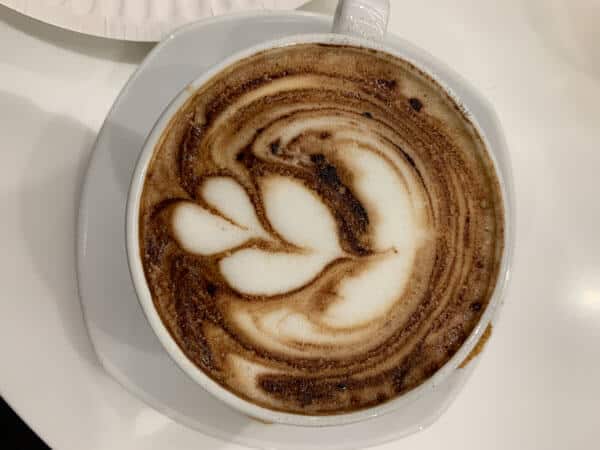 cappucino coffee with a leaf made up of milk foam in a white cup