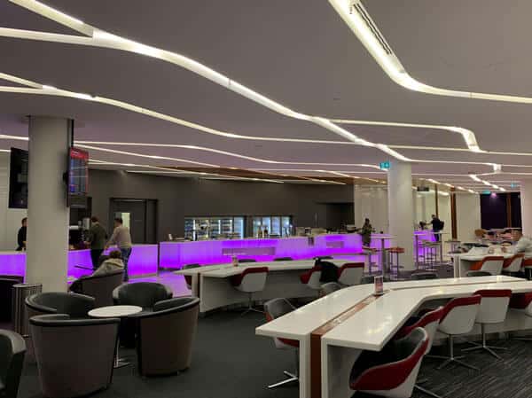 virgin australia perth business lounge with purple mood lighting and white tables and chairs