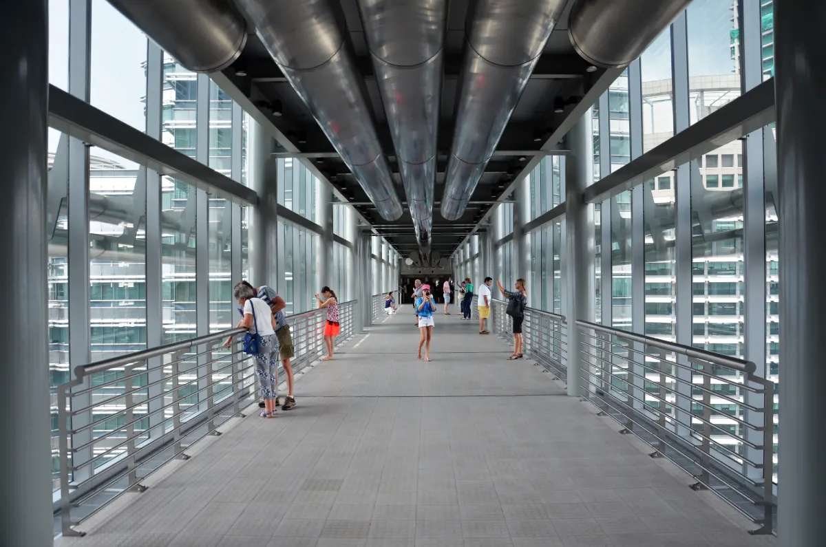 people on a steel skybridge high up over city